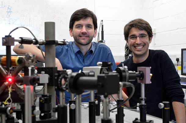 Amalio Fernández-Pacheco, investigador principal del proyecto (izquierda) y Dédalo Sanz-Hernández, líder del trabajo (derecha) en el Laboratorio Cavendish de la Universidad de Cambridge, junto al equipo láser utilizado para la lectura de información en las nanoestructuras 3D. / Dédalo Sanz-Hernández