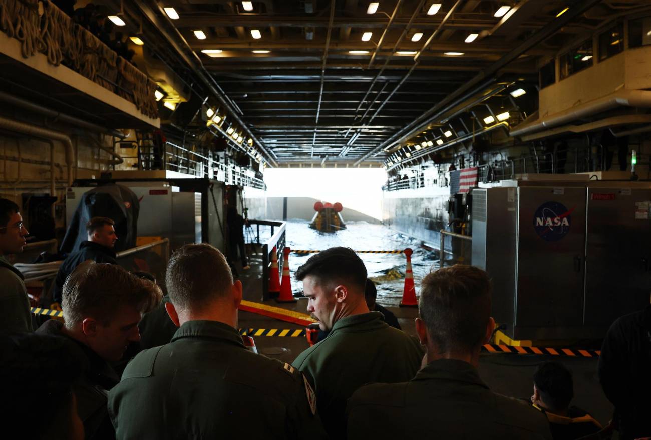 Pilotos de la Marina de los EE UU se reúnen después de que la cápsula Orion de la NASA fuera llevada a la cubierta del U.S.S. Portland tras amerizar en el Pacífico. / EFE/EPA/Mario Tama/POOL
