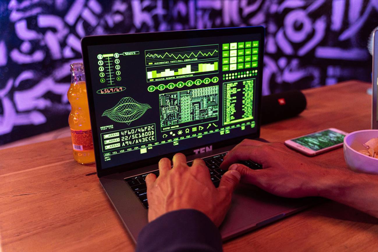 Manos de una persona escribiendo en un ordenador portátil con una pantalla llena de gráficos.