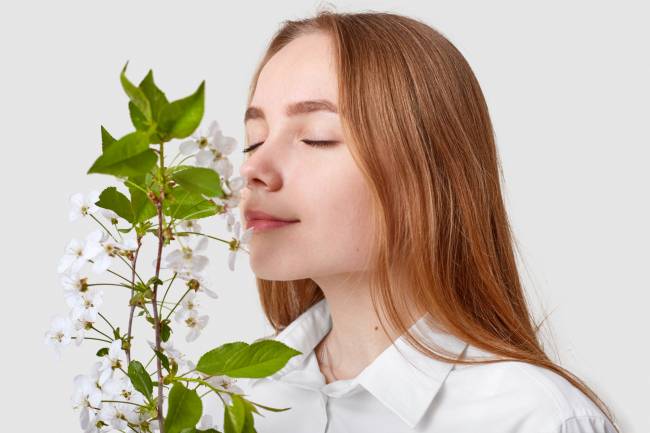 mujer oliendo una planta