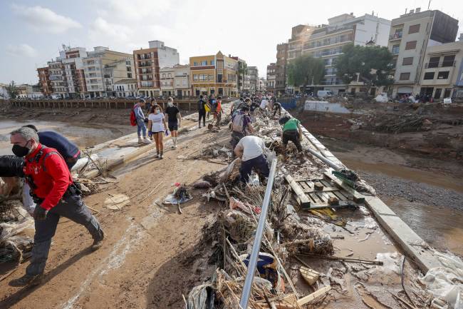 Decenas de voluntarios trabajan para despejar uno de los puentes de Paiporta