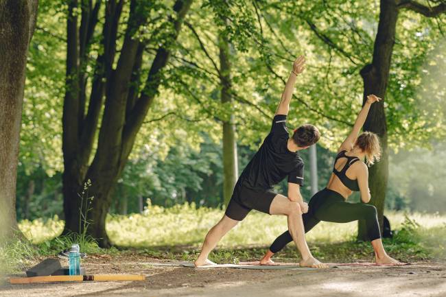 una pareja haciendo yoga en el parque