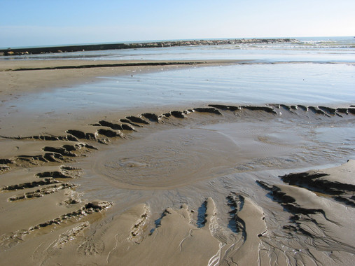<p>Agua subterránea descargando en el mar justo antes de la línea de costa, formando un pequeño torrente superficial en la playa de Les Fuentes (Alcocéber, Castelló). / J. Garcia-Orellana.</p>