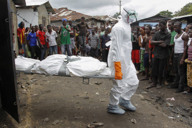 <p>Varios operarios trasladan el cadáver de una víctima del virus del Ébola en una barriada de Logan, en las afueras de Monrovia (Liberia), el 30 de septiembre del 2014. / EFE</p>