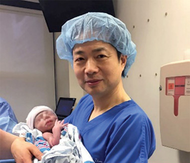 <p>John Zhang sostiene al bebé en el momento de su nacimiento. / <em>New Scientist</em></p>