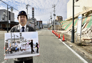 <p>Un vecino de Namie muestra la foto de un día festivo en su ciudad antes de quedar desierta por el accidente nuclear. / EFE</p>